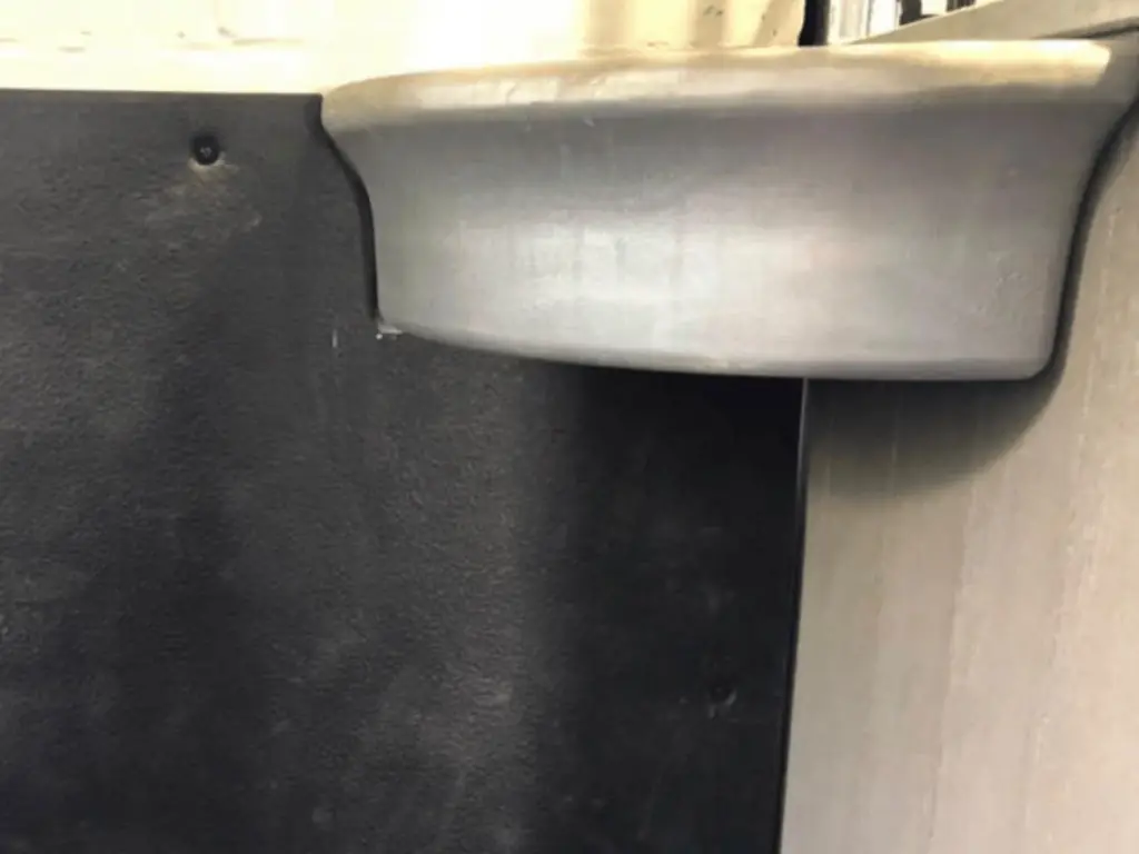 Zwart rubber wandpaneel op maat gesneden met een uitsparing rond een voerbak